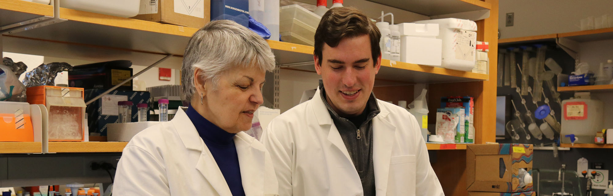 Mentor and mentee wearing lab coats in a lab